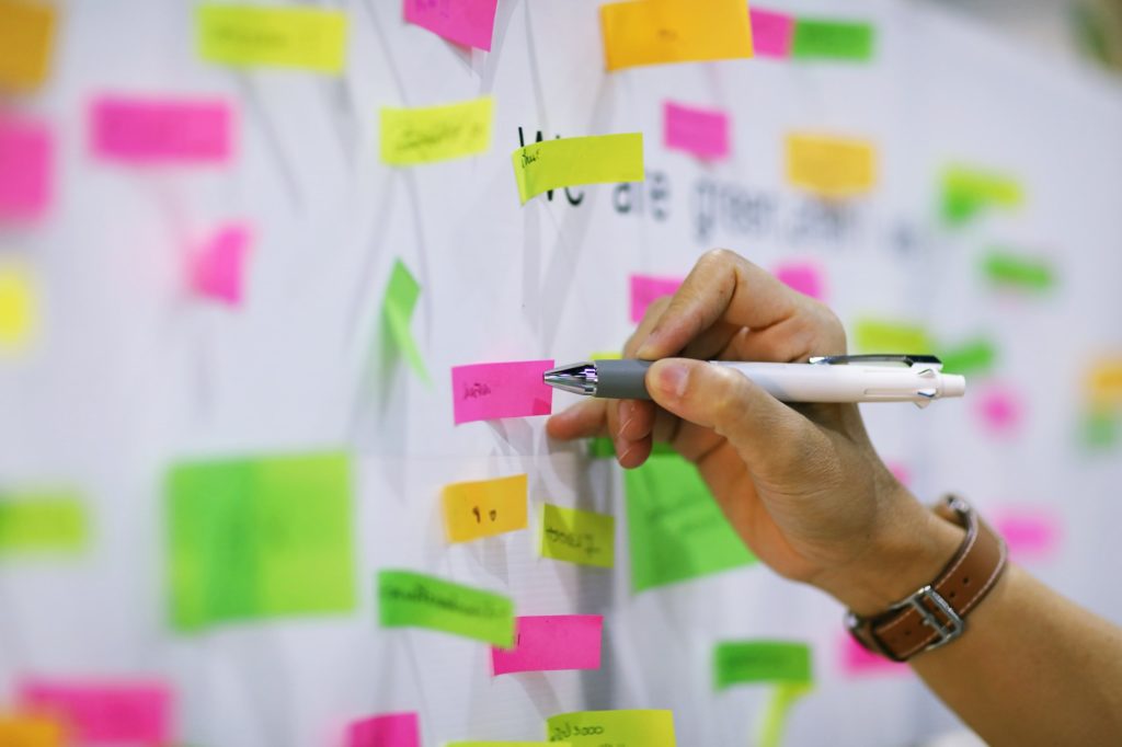 People hand write on whiteboard closeup blur colors post-it paper background